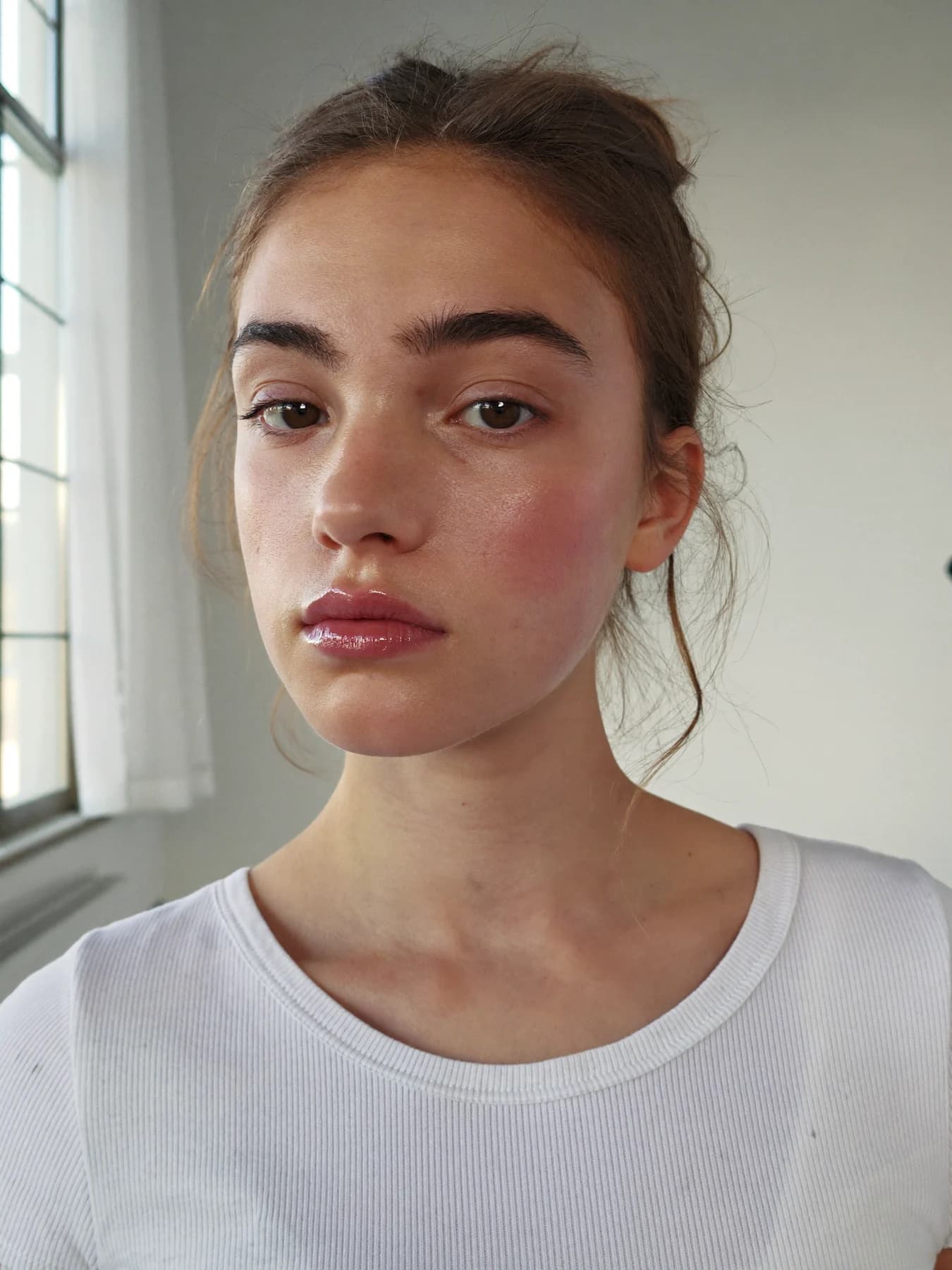 Ung kvinde med frisk hud og naturlig makeup i dagslys